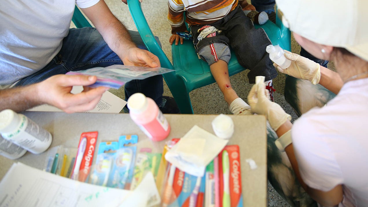 Medical volunteers clean a cut on a child's leg. 