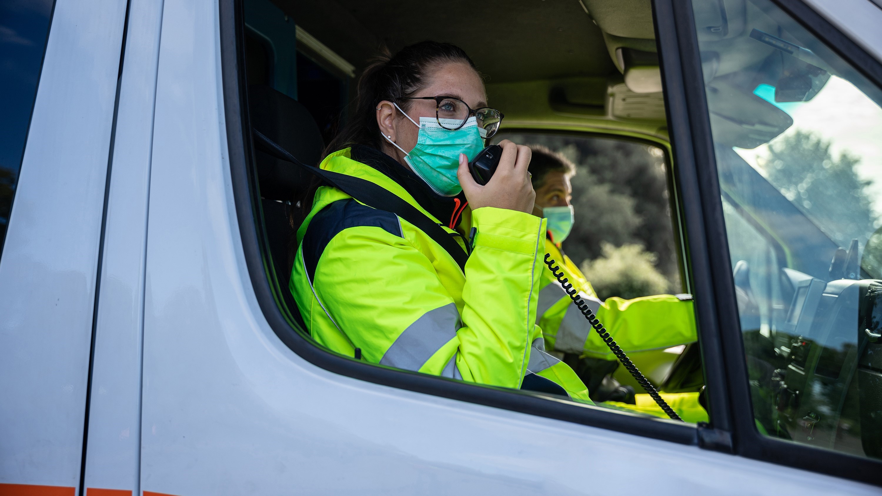 A paramedic uses a two-way radio while sitting in an ambulance.