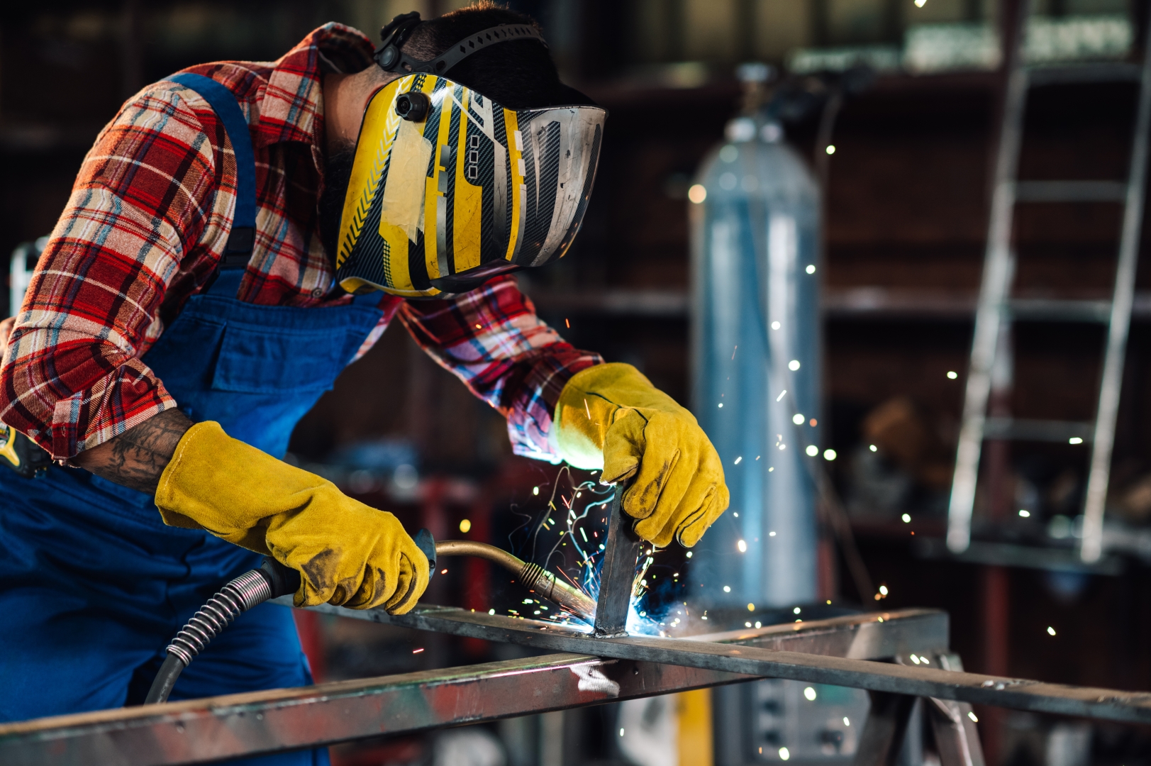 Welder wearing safety gear creates a metal construction using welding equipment.