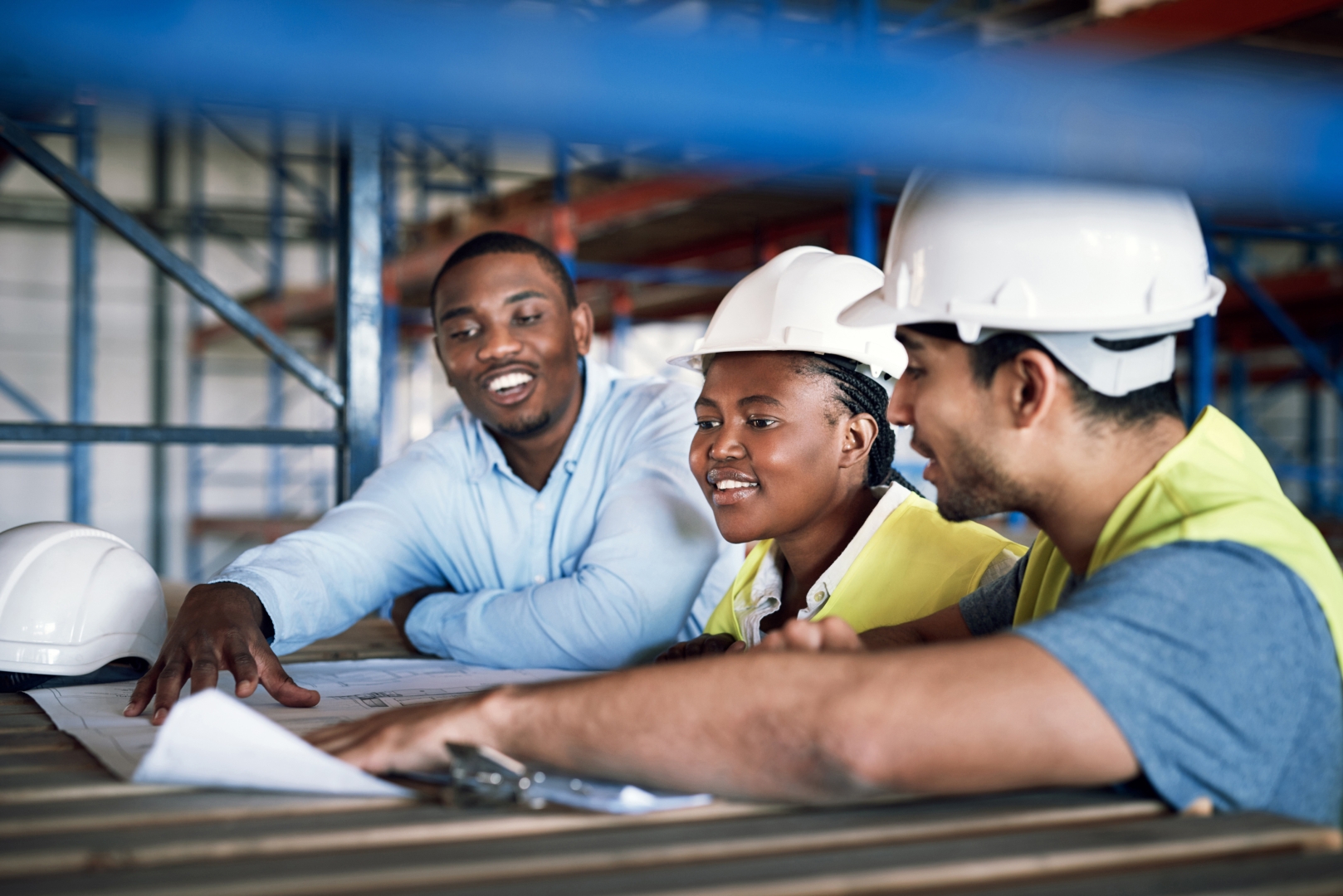 Three people look at blueprint.