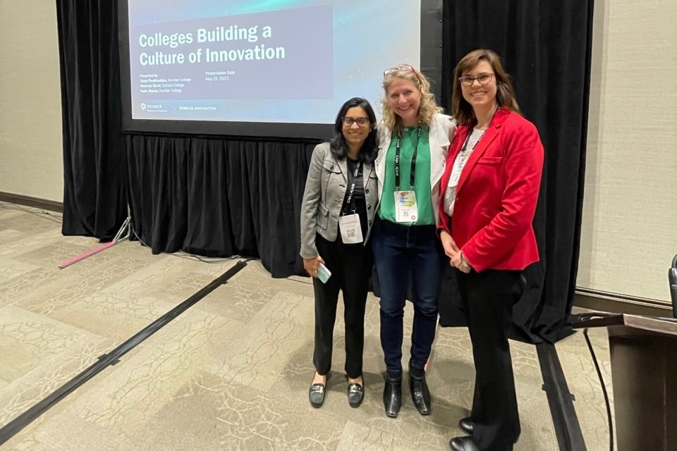 Three women stand in front of a presentation screen at the CARA conference.