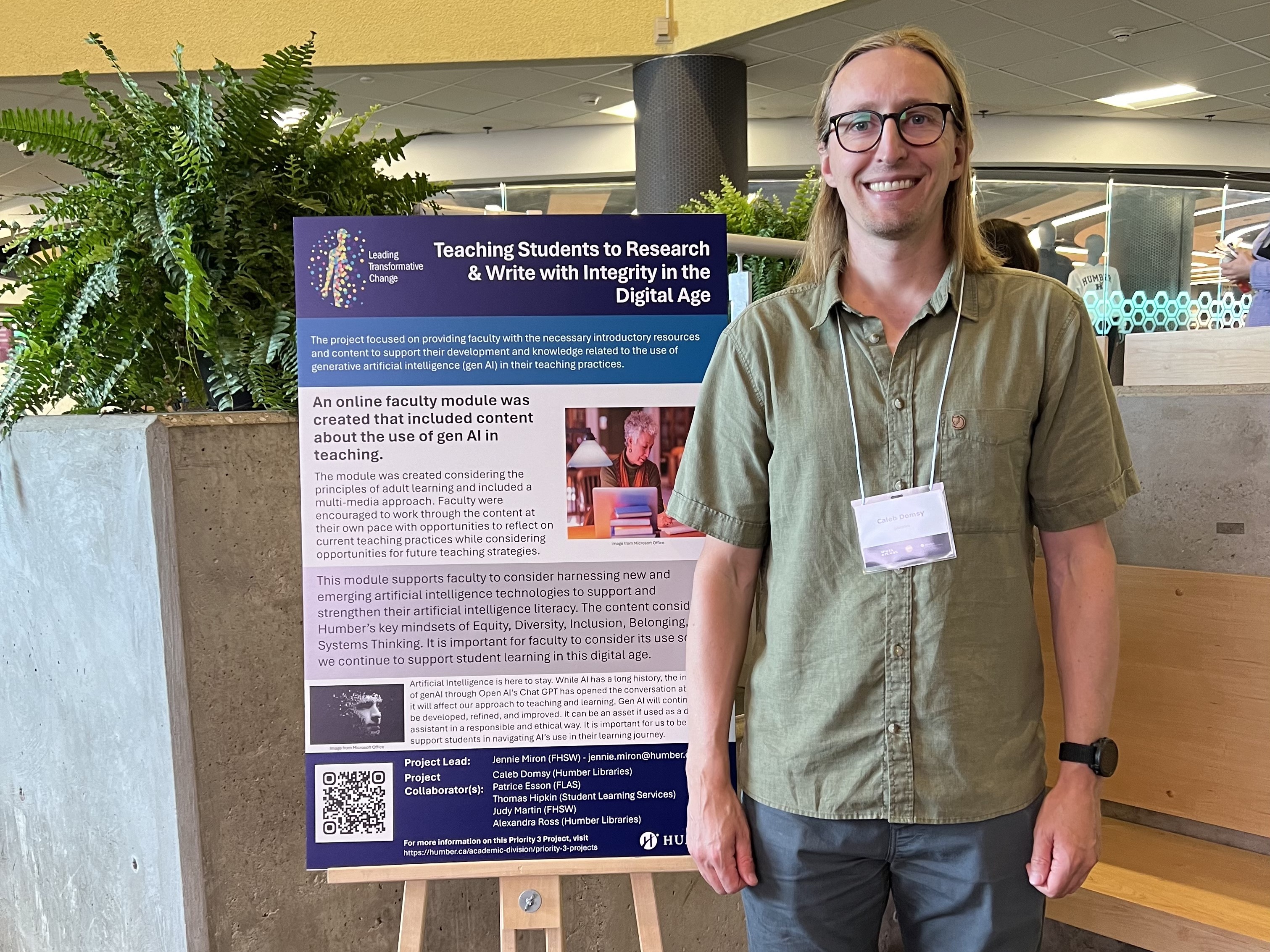 A man wearing a green shirt stands in front of poster presentation.