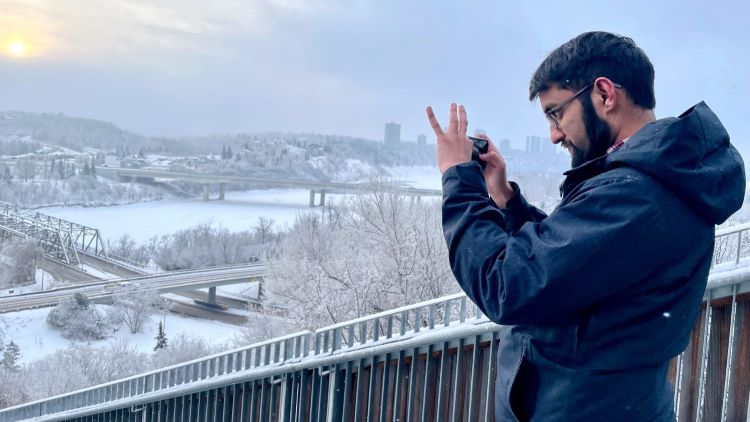 A man takes a photo of a snowy landspace.