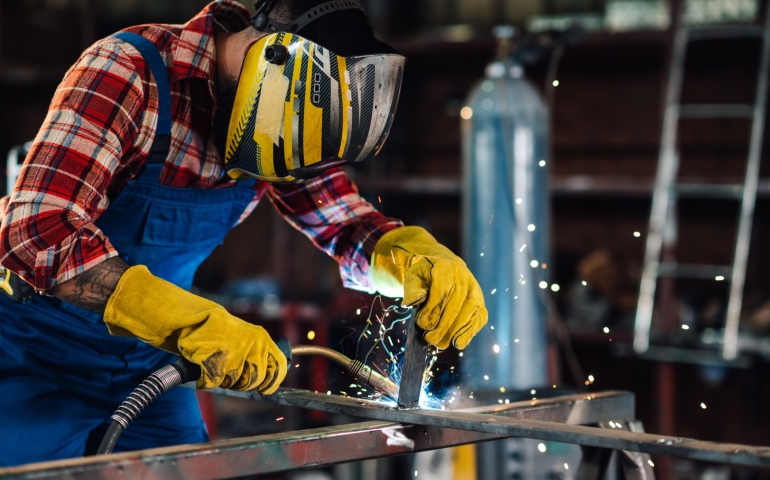 Welder wearing safety gear creates a metal construction using welding equipment.