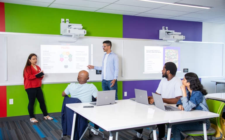 Five people look at projector screen in a HIVE classroom.