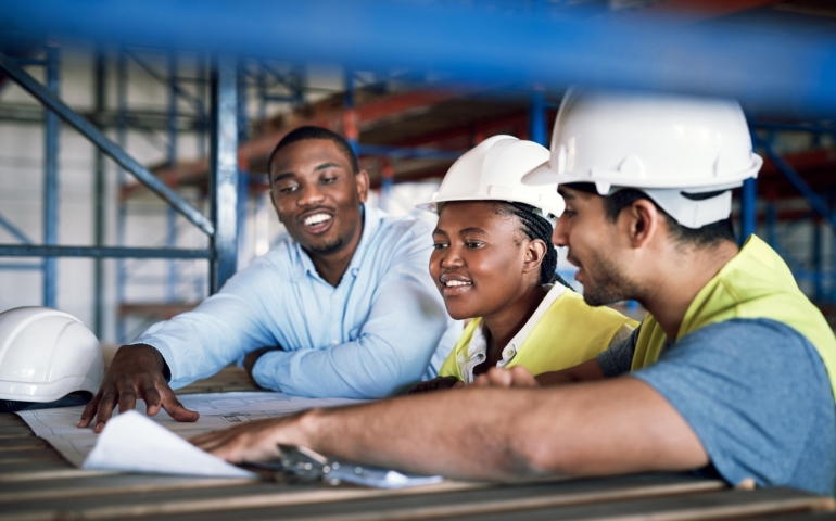 Three people look at blueprint.