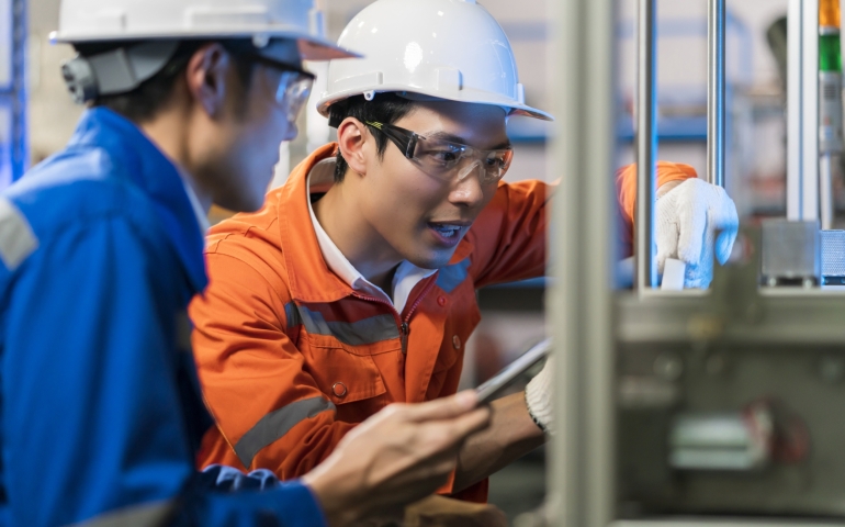 A man wearing safety equipment works with on an instrustrial machine